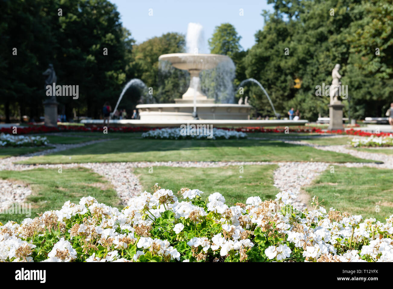 Warsaw, Poland tourists by water fountain in summer Saxon Gardens Park with spraying splashing sculptures and flower bed Stock Photo