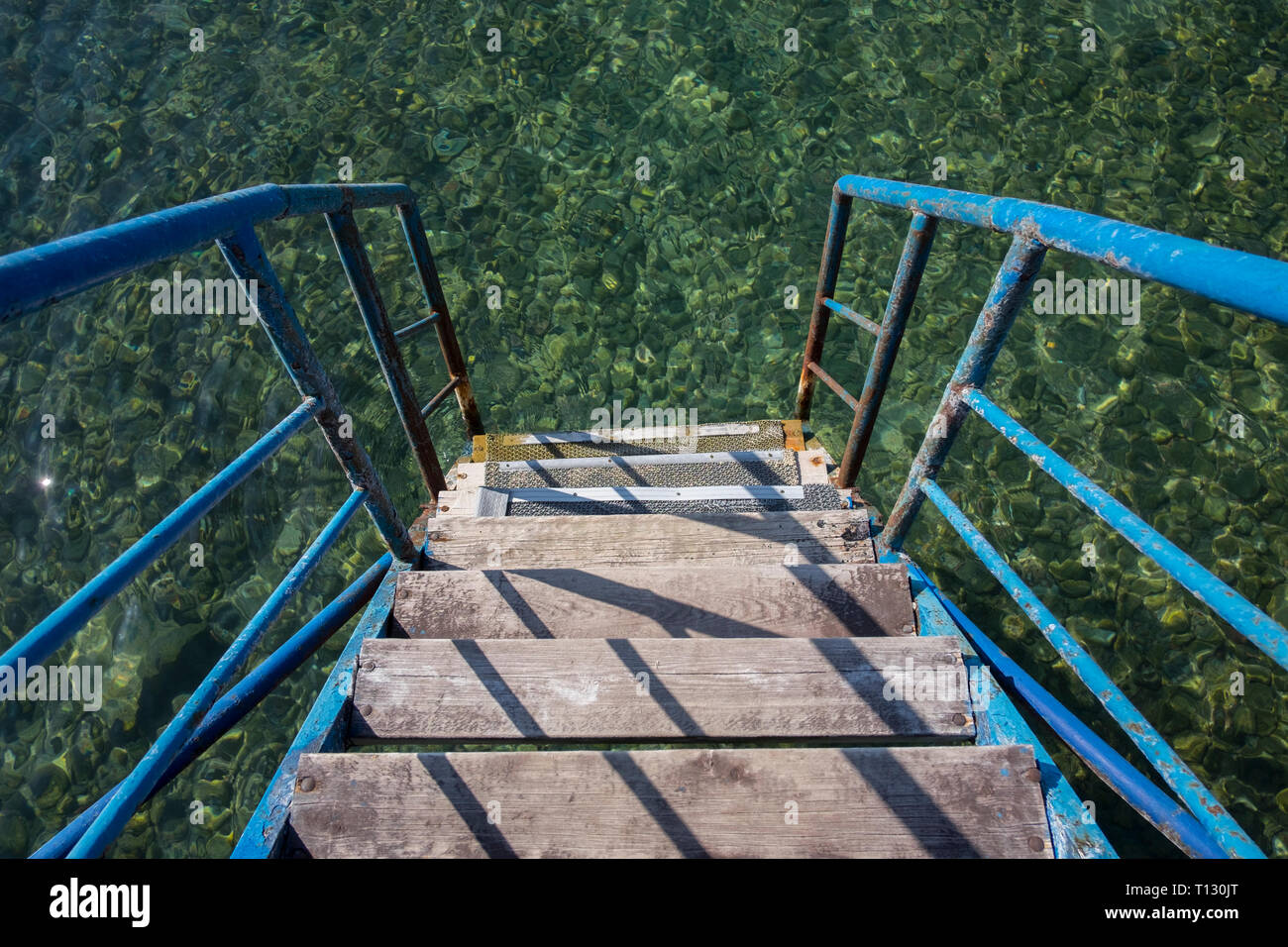 Steps leading down to the cool, clear greenish water at lake Issyk Kul in Kyrgyzstan. Stock Photo