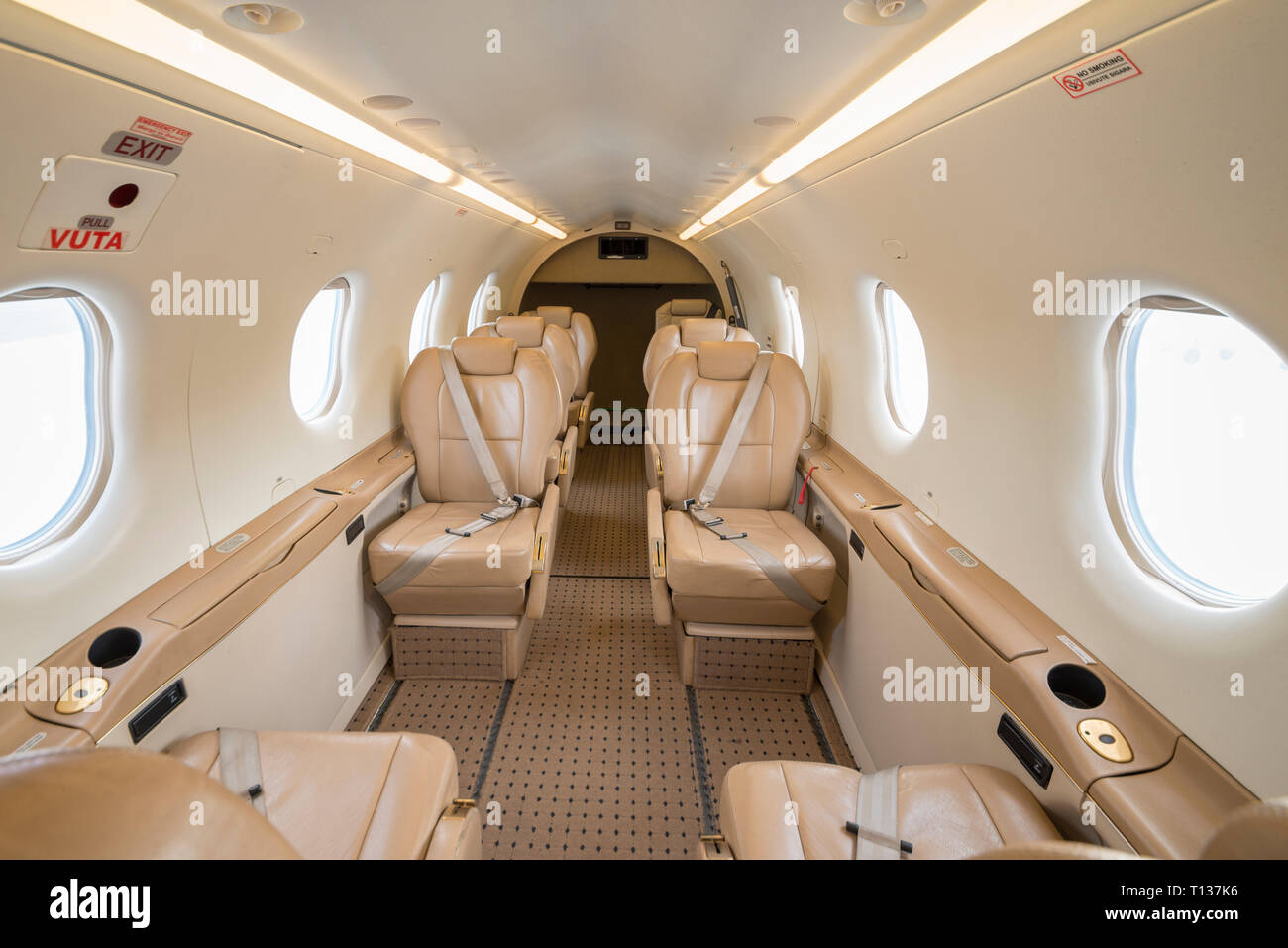 Interior view, looking aft, of a Pilatus PC12 turboprop aircraft with leather seating. Window light illuminated the interior. Stock Photo