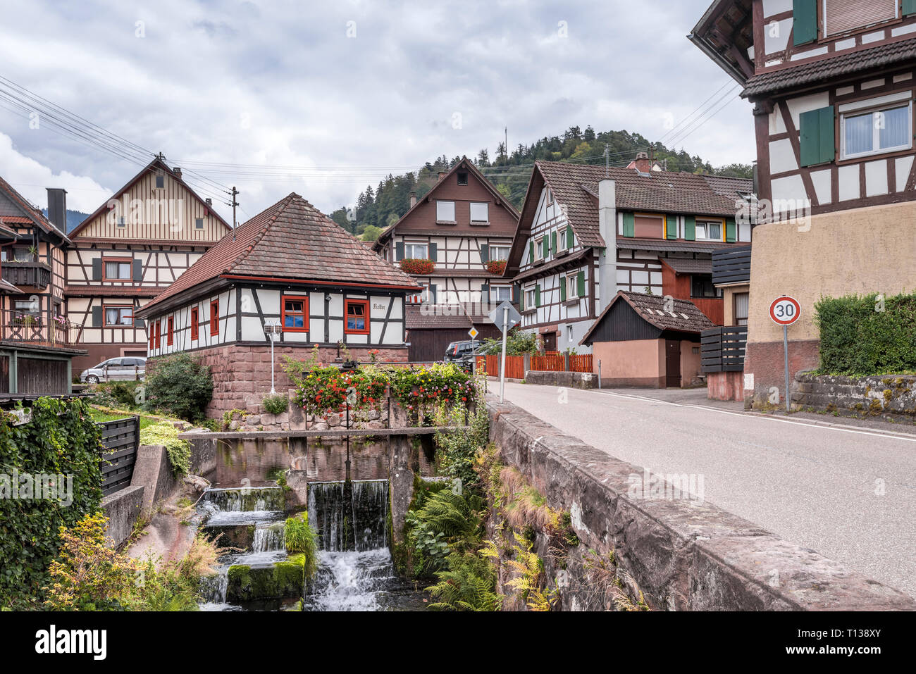 half-timbered houses and brook with waterfall in Murg valley of the Northern Black Forest, Germany, village Reichenbach, town Gernsbach Stock Photo