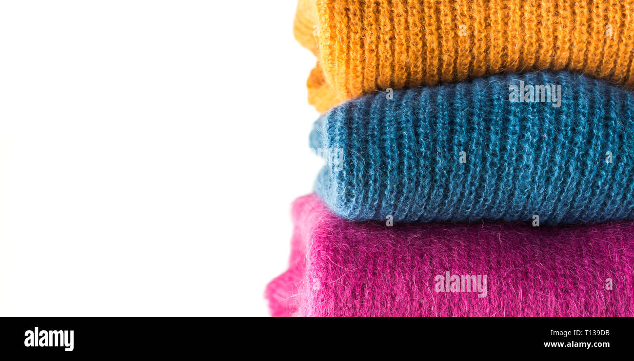 Pile of cozy winter woolen sweaters isolated on white