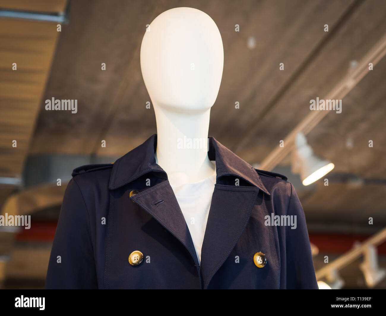 White mannequin wearing blue trench in a fast fashion store Stock Photo