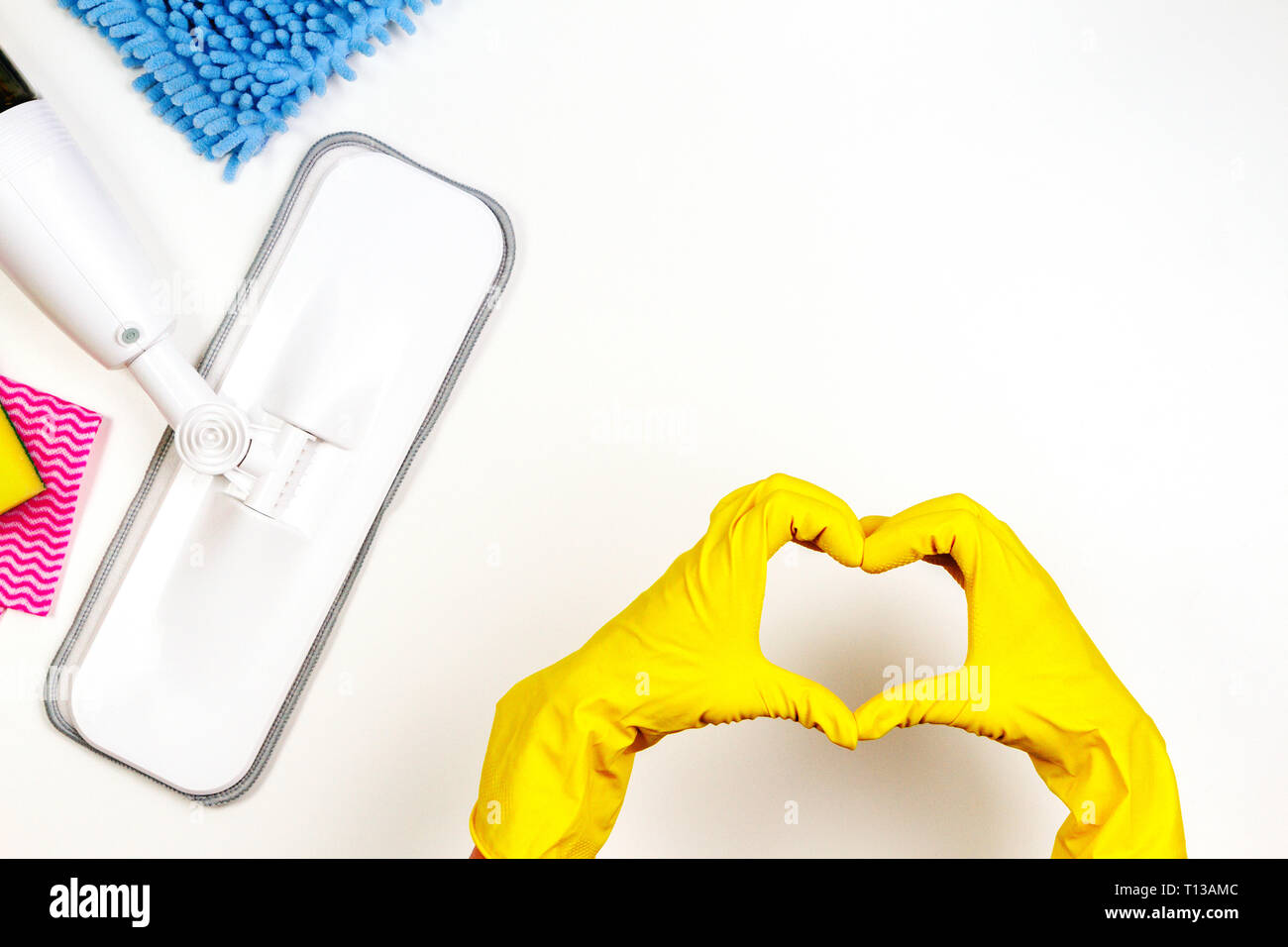 Housework, housekeeping, household, cleaning service concept. Cleaning spray mop, rags, sponges and woman hand with rubber gloves in the form of heart Stock Photo