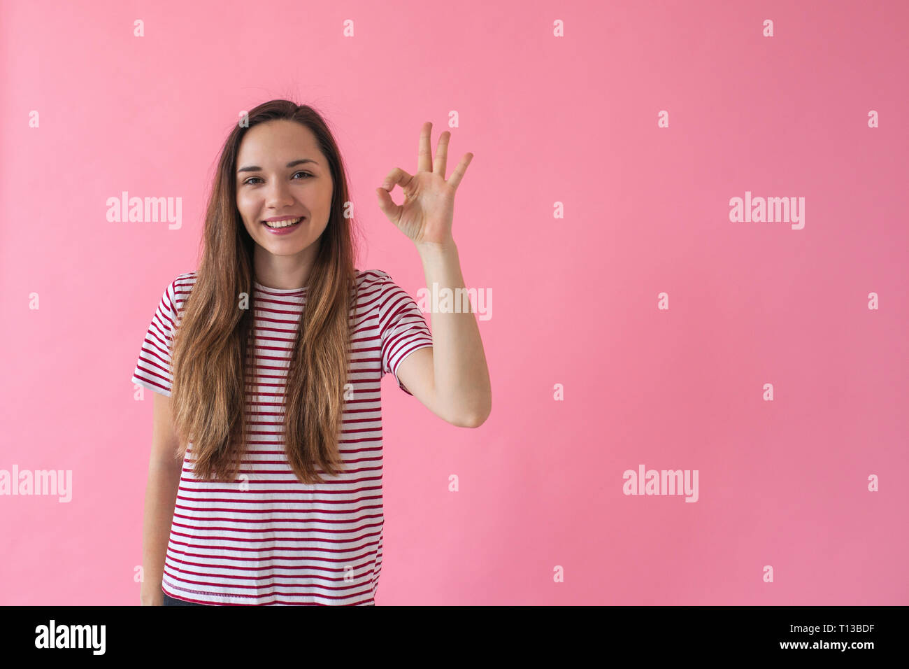 Positive Smiling Girl On A Pink Background Shows Fingers Gesture Meaning Ok Stock Photo Alamy