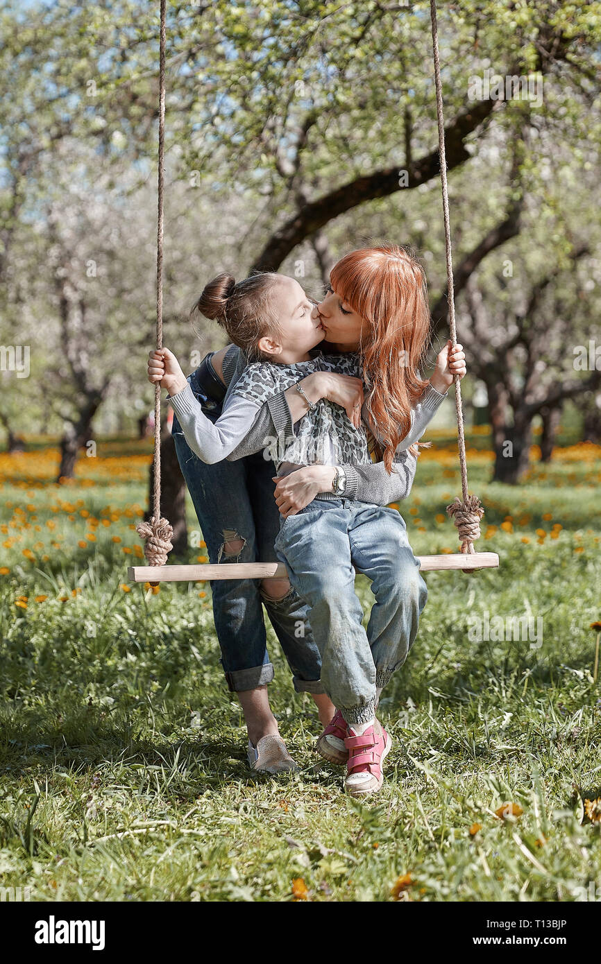 mom and her little daughter on a swing in the summer day Stock Photo