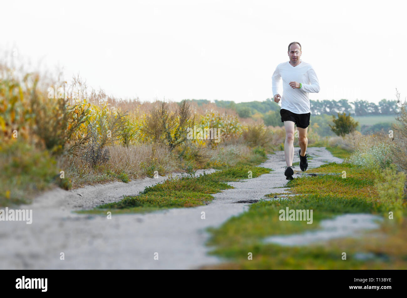 Middle age man running alone outdoors countryside at fall Stock Photo