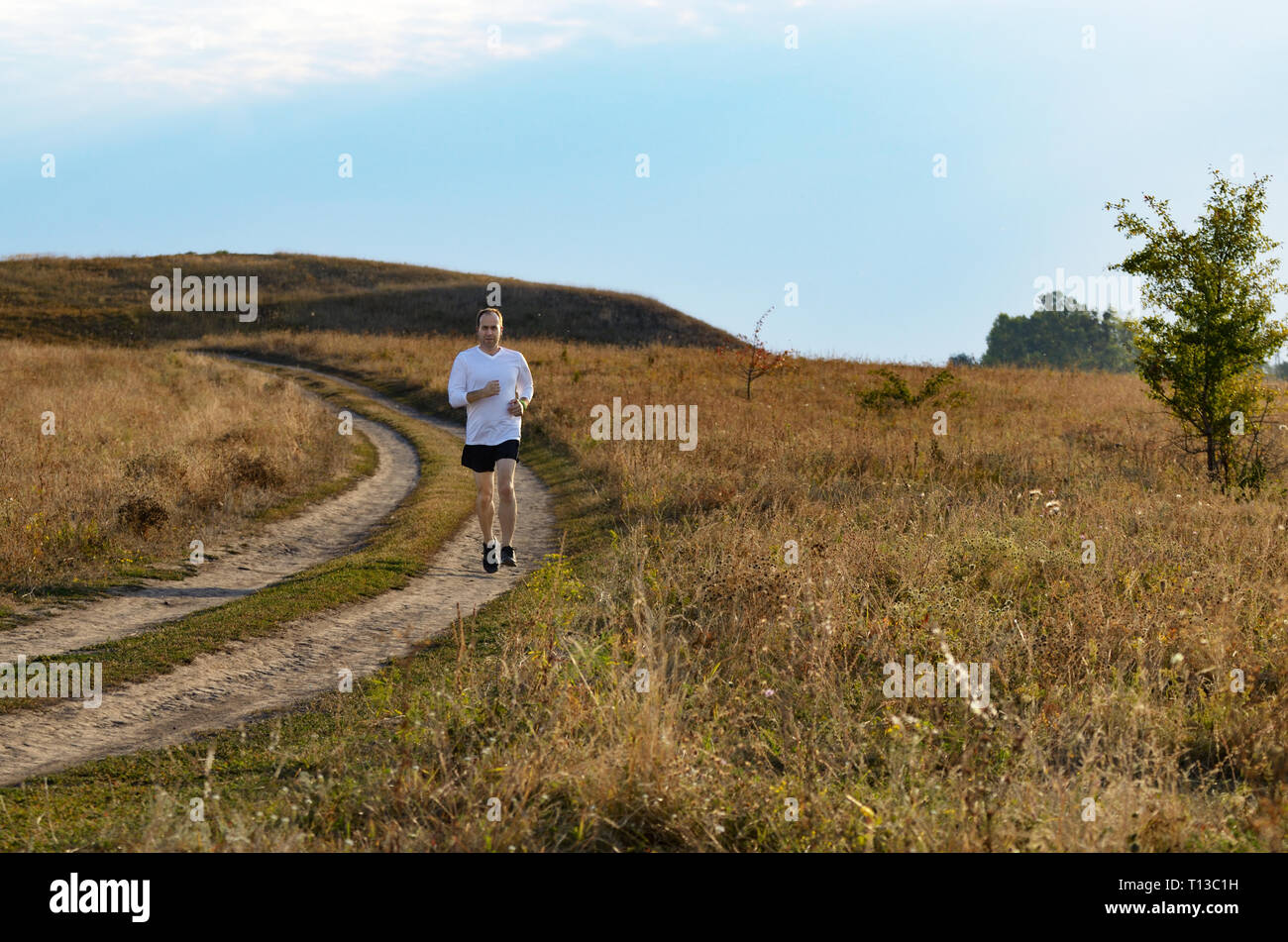 Middle age man running alone outdoors countryside at fall Stock Photo