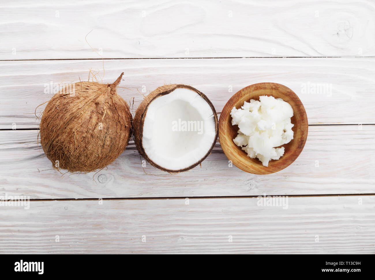 Flat lay background of coconut, coconut shell, hard oil in wooden bowl on white wooden table Stock Photo