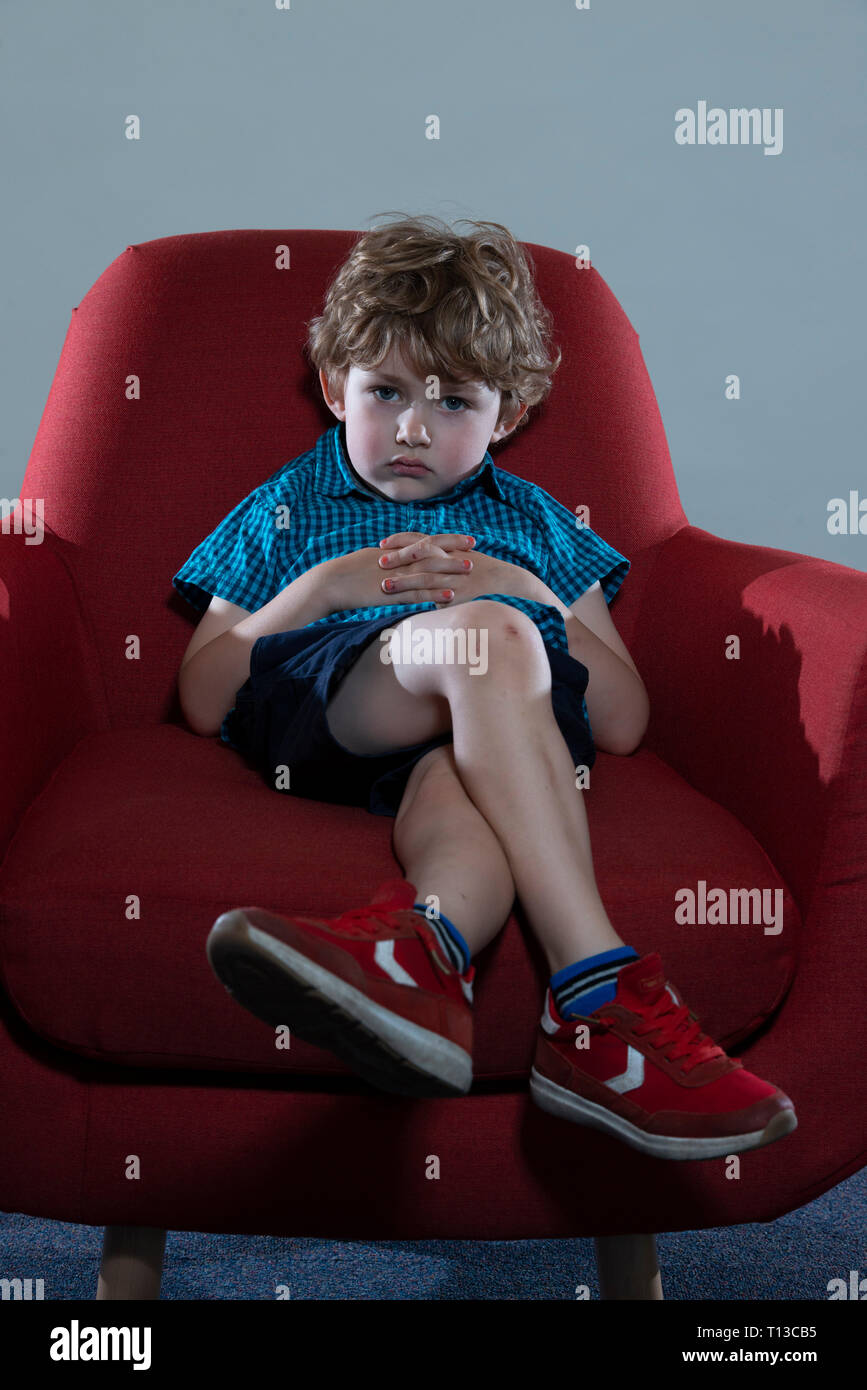 a board young white boy being restless and fed up on a colourful sofa