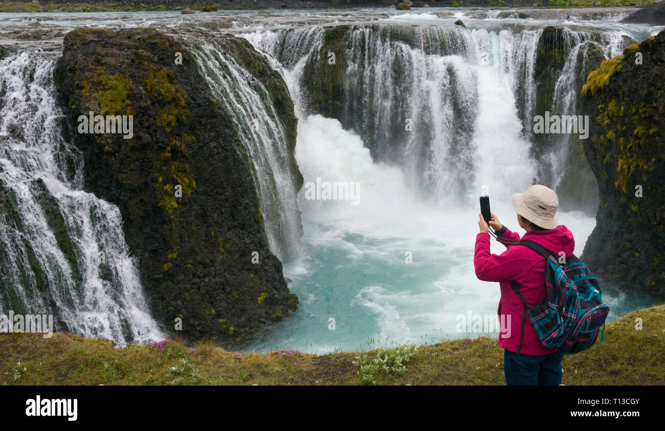 Tourist photographing Sigoldu Waterfall, Iceland Stock Photo