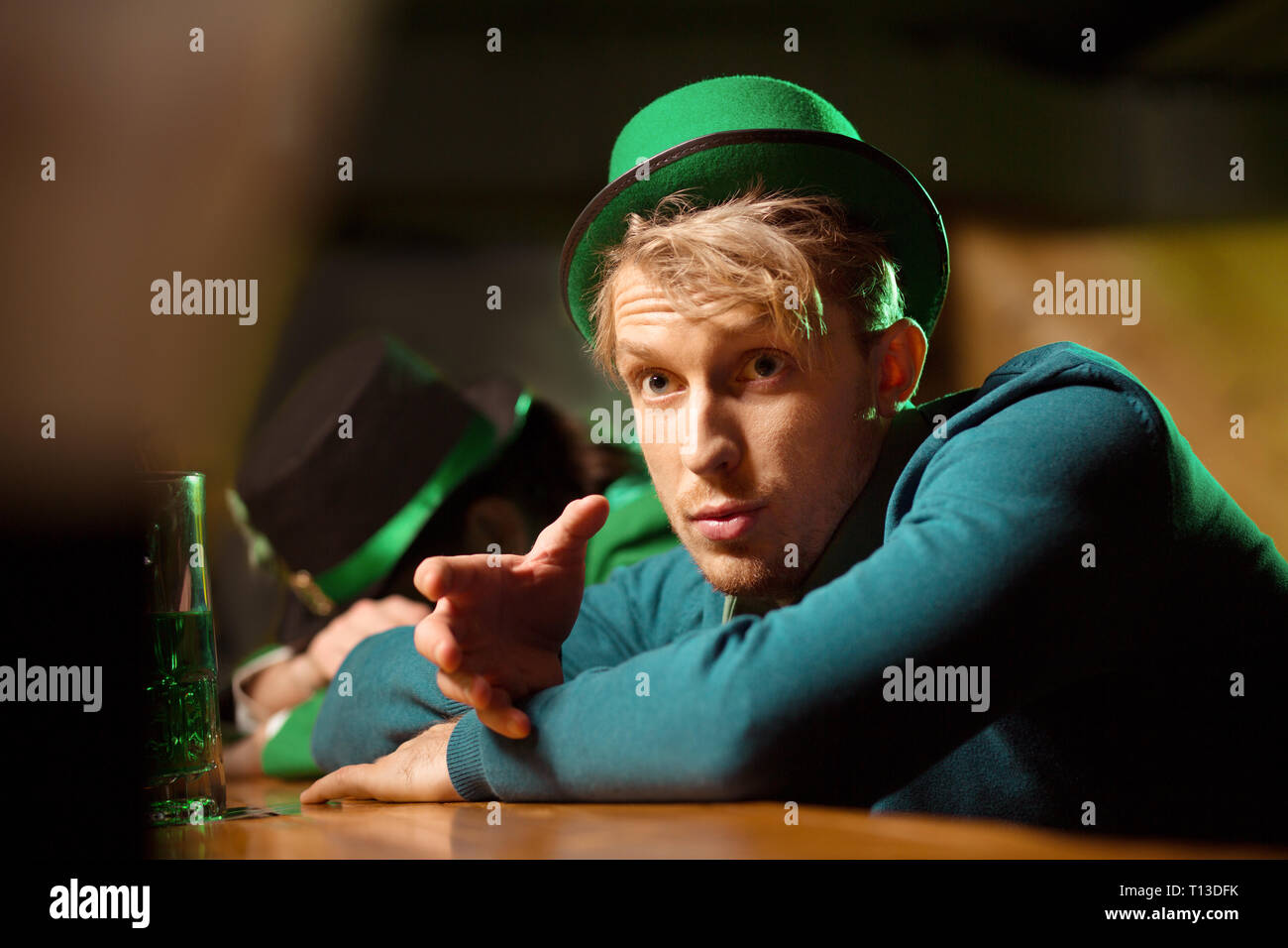 Fair-haired young handsome man in a green looking surprised Stock Photo