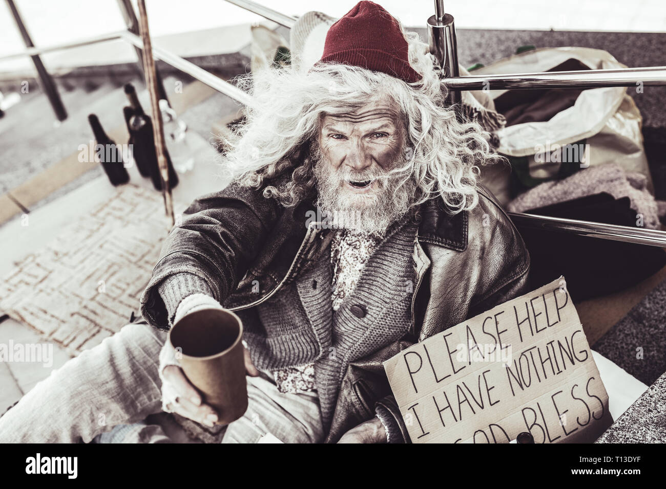 Homeless old man trying to move to pity pedestrians. Stock Photo