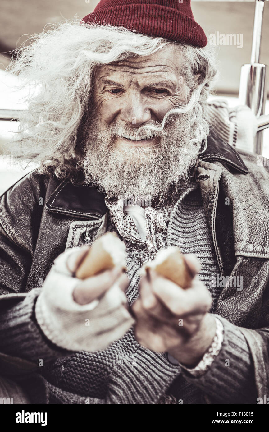 Portrait of beggar taking bun he found for breakfast. Stock Photo