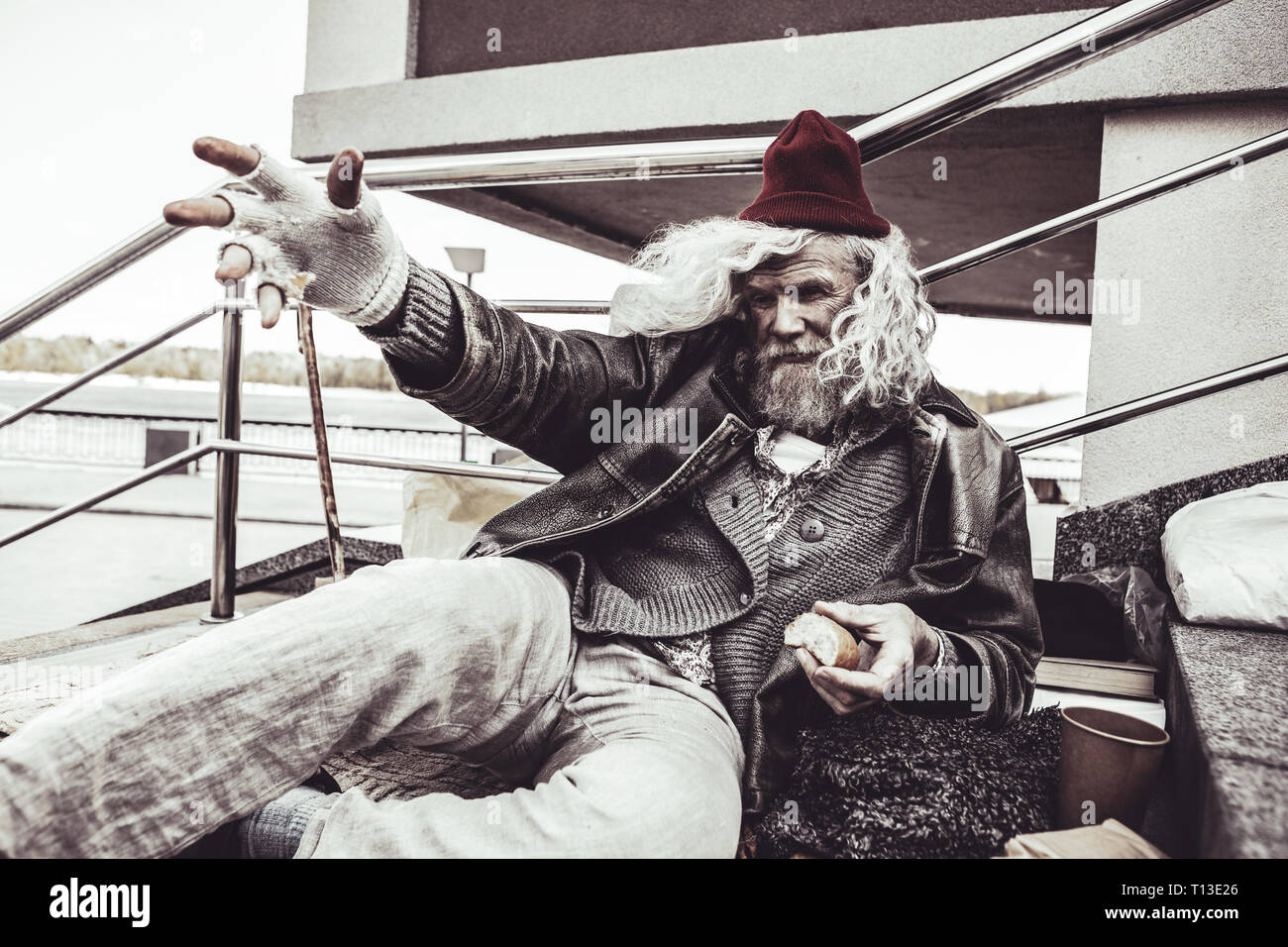 Drunk homeless man swearing at pedestrians while stretching. Stock Photo