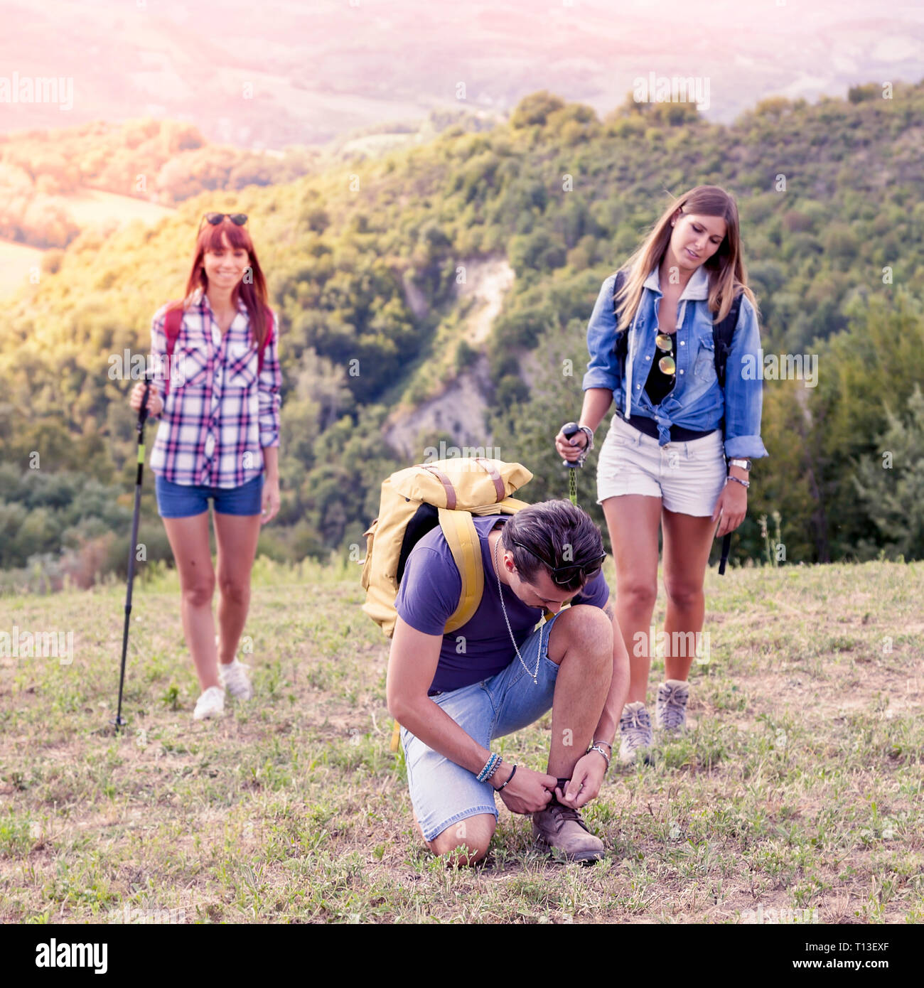 group of young hikers walking toward the horizon over the mountain ...