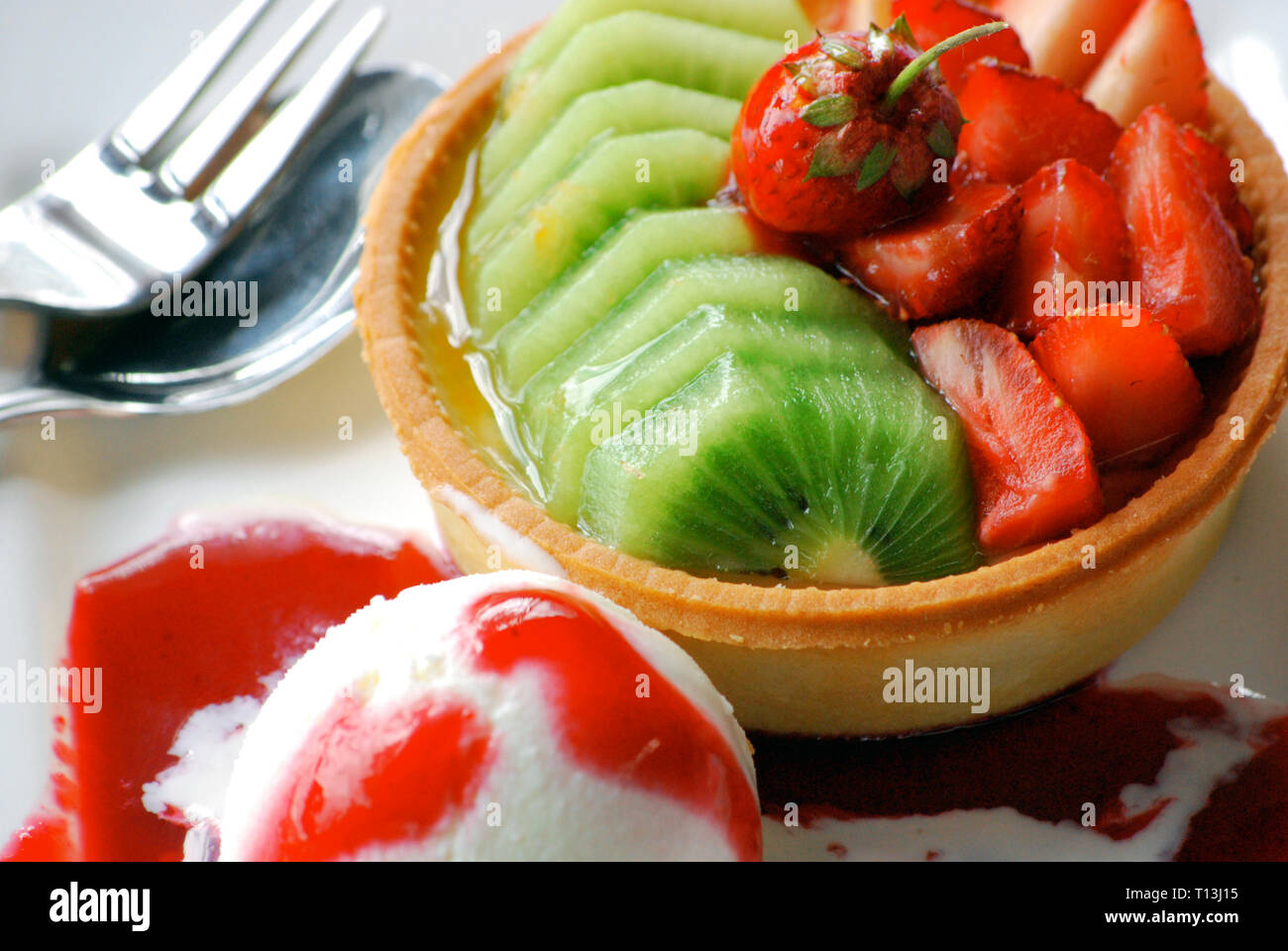 Sliced glistening Kiwi fruit and Strawberries in a bowl, with a scoop ice-cream, Stock Photo