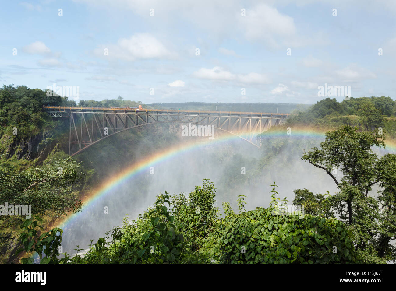 Rainbow curving like bridge over gorge in Victoria Falls Africa Stock Photo