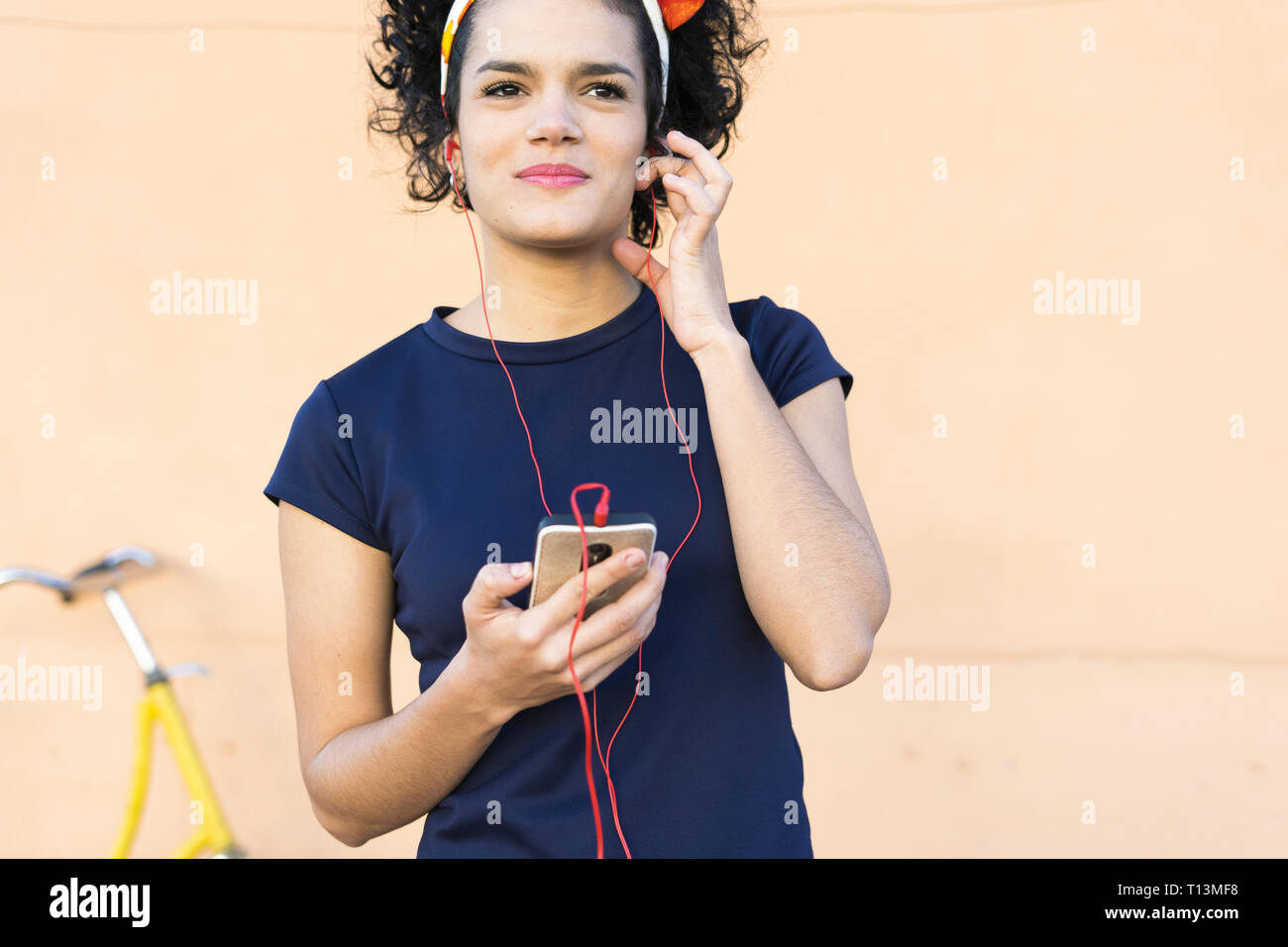 Smiling young woman with smartphone listening to music Stock Photo