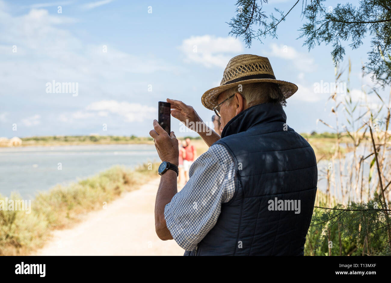 Italy, Sicily, Vendicari nature reserve, senior man taking a smartphone picture Stock Photo