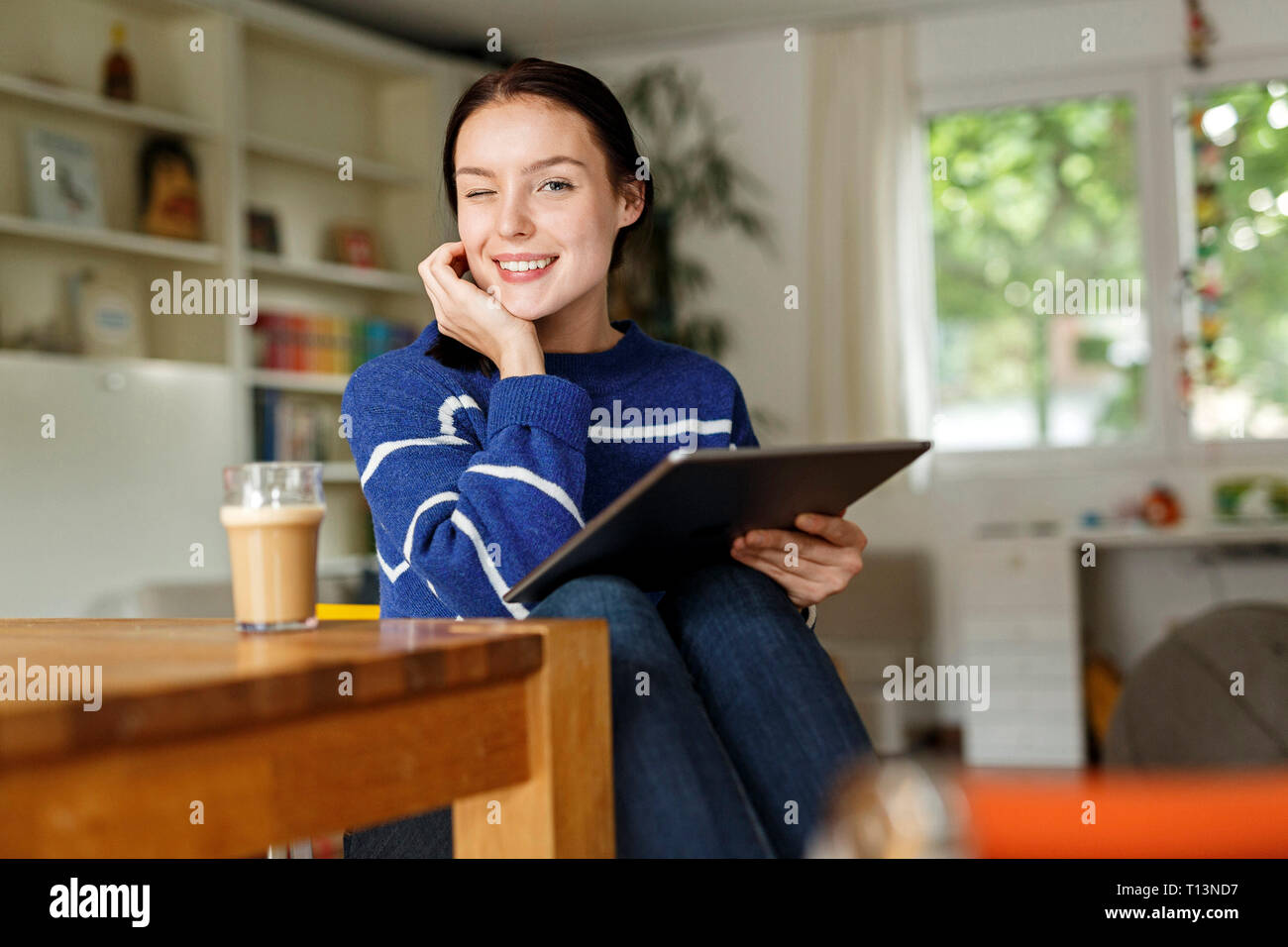 Young woman sitting at home, using digital tablet Stock Photo