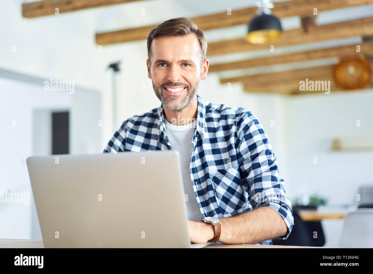 Portrait of man working remotely on laptop and looking at camera Stock Photo