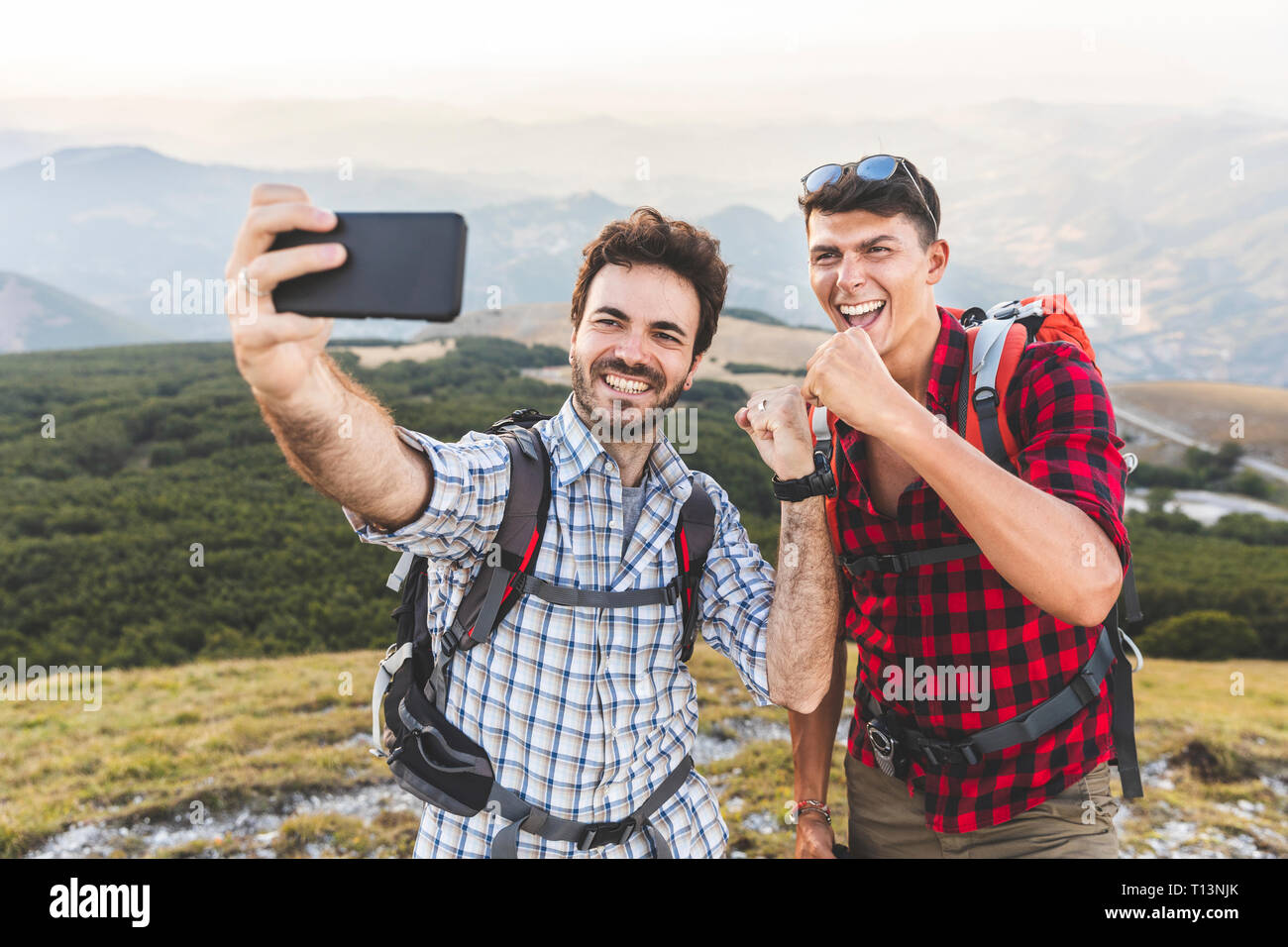 Italy, Monte Nerone, two happy hikers on top of a mountain taking a ...