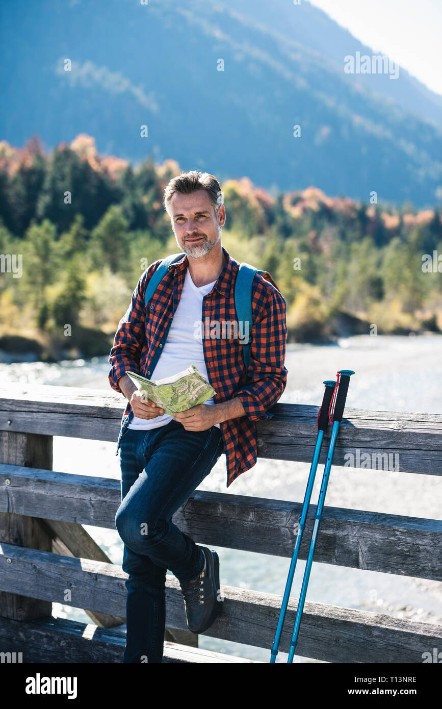 Austria, Alps, man on a hiking trip with map on a bridge Stock Photo