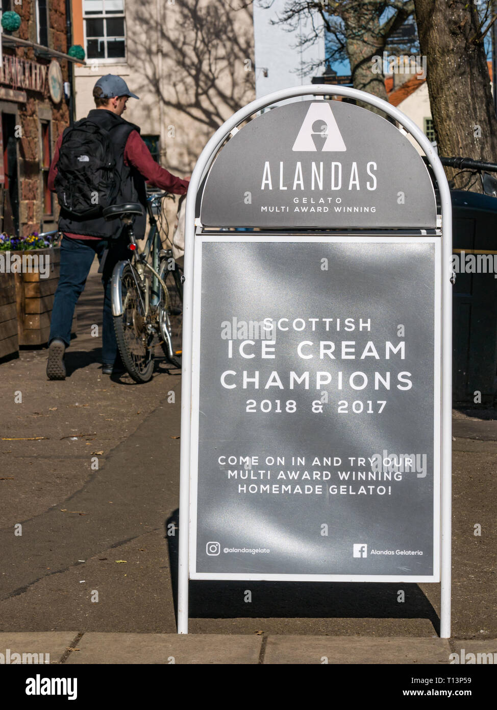 Cyclist walking past Alandas award winning ice cream gelateria, North Berwick, East Lothian, Scotland, UK Stock Photo