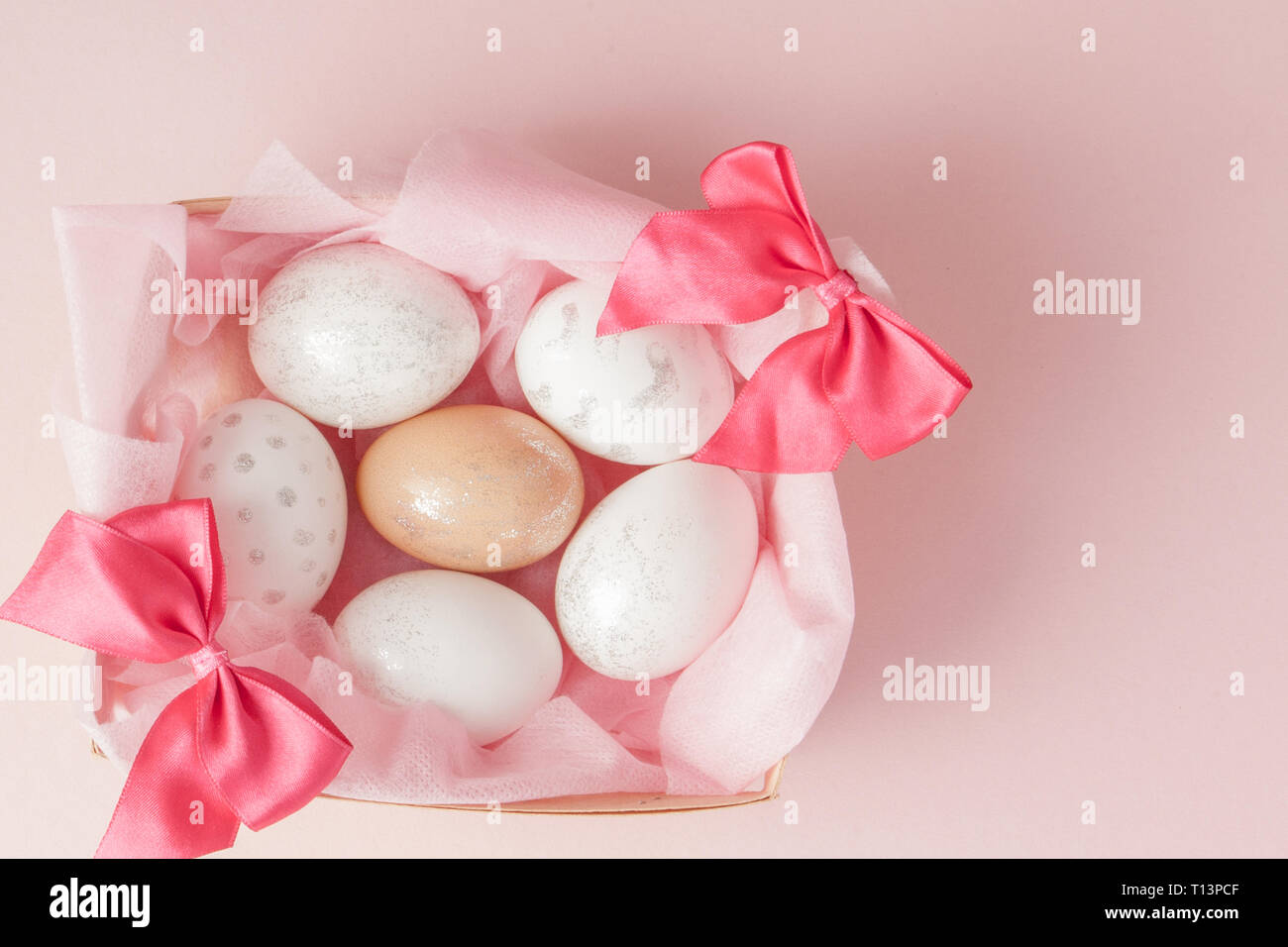 White Easter eggs in a nest on pink background. Design pastel tone in ...
