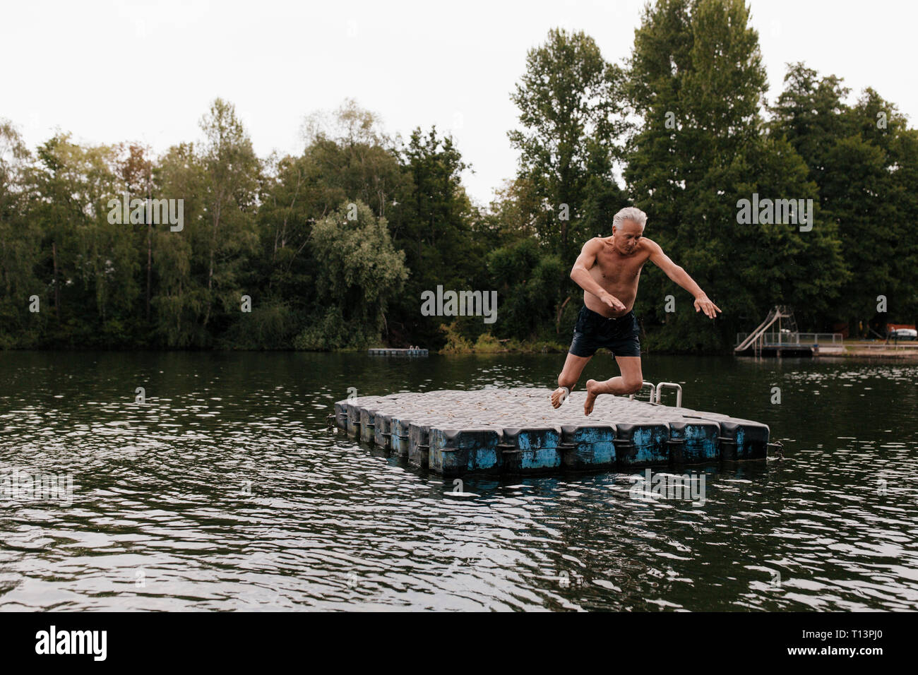 Senior man jumping from raft in a lake Stock Photo