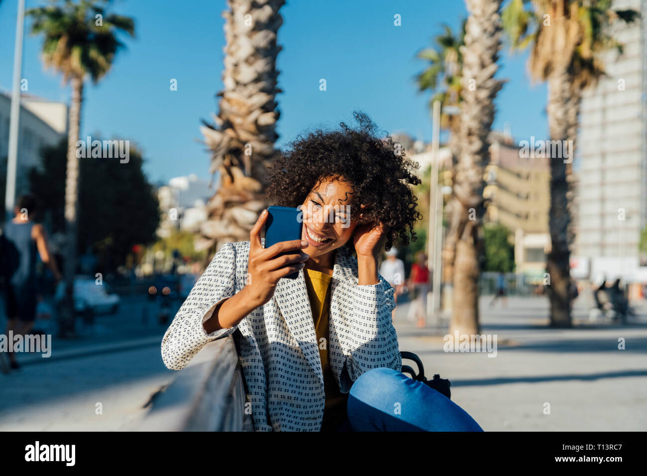 Beautiful woman sitting on a bench in the city, using smartphone Stock Photo