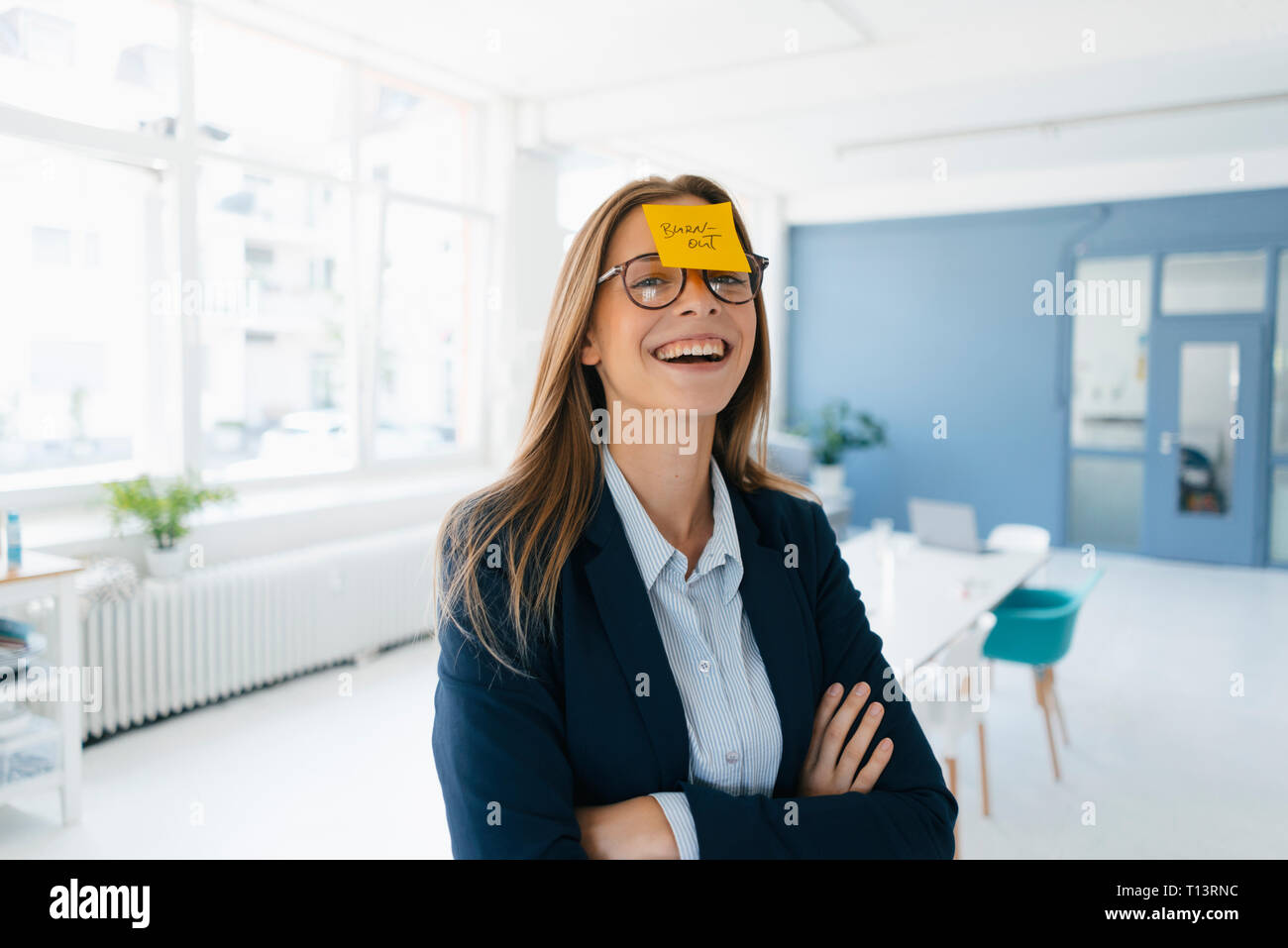 Young businesswman with yellow sticky note on her forehead, saying 'burnout' Stock Photo