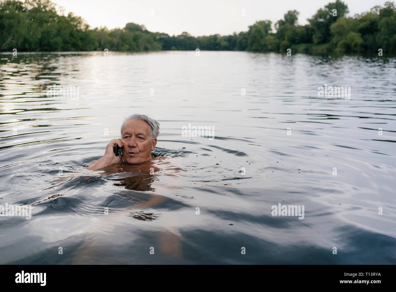 Senior man talking on cell phone in a lake Stock Photo