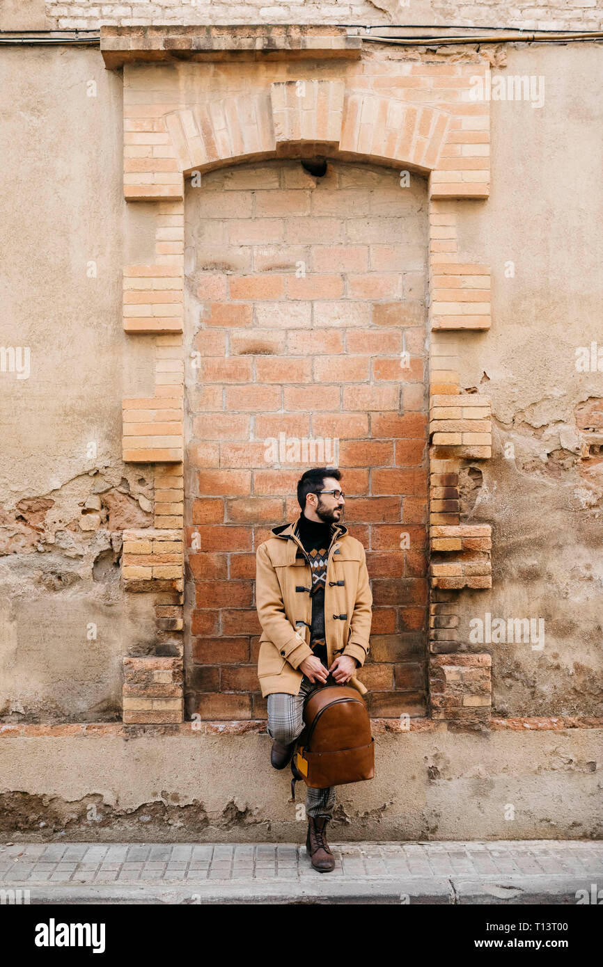 Spain, Igualada,man with backpack standing at rundown building Stock Photo