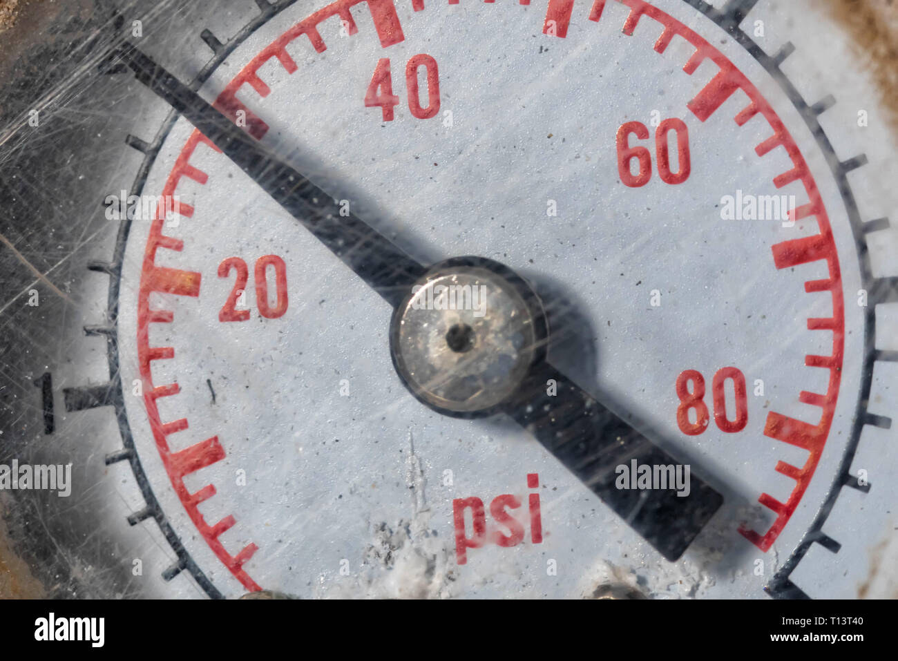 old rusty tire pressure gauge with red numbers on a white background
