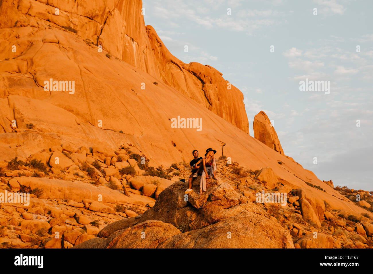 Namibia, Spitzkoppe, couple sitting on a rock at sunset Stock Photo