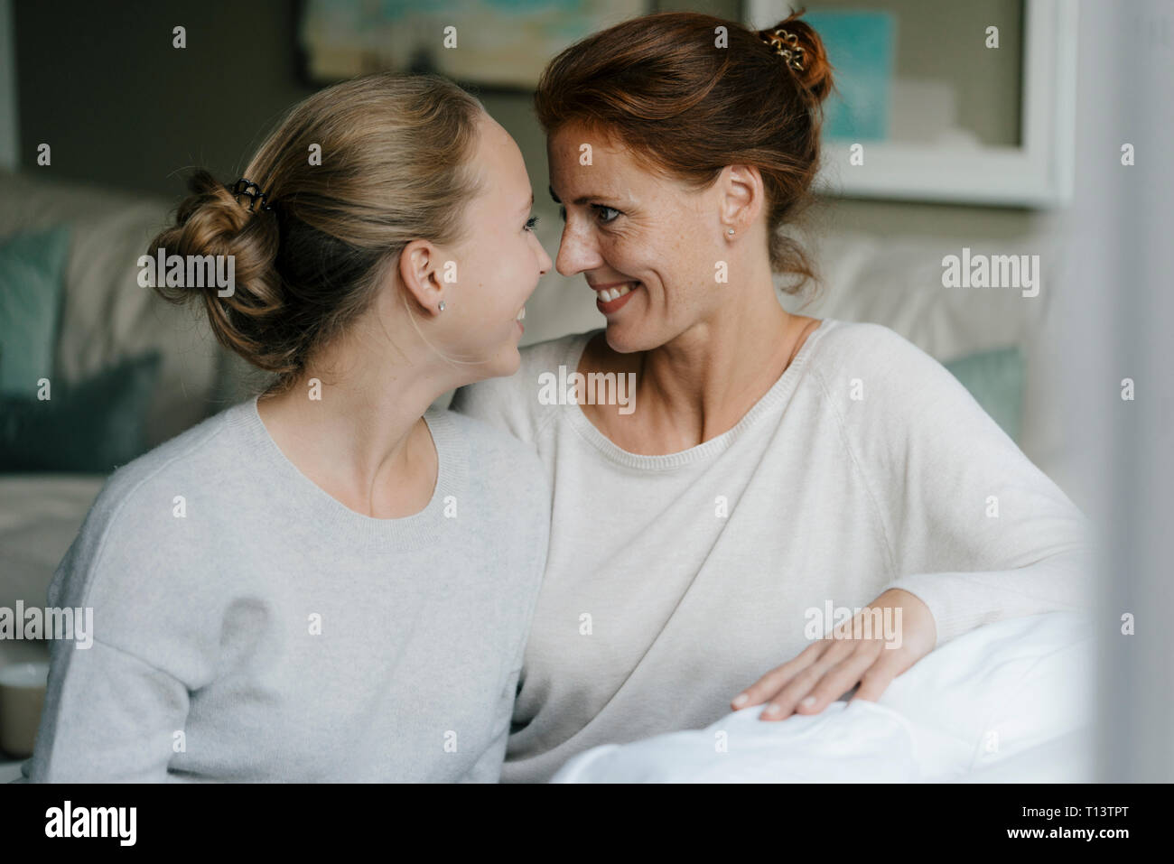 Happy mother with teenage girl face to face on couch at home Stock Photo