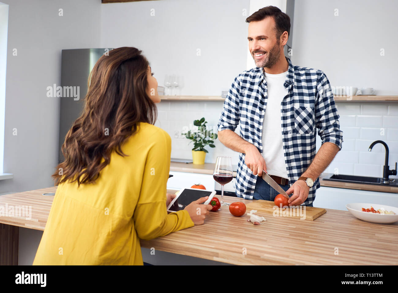 Affectionate couple in kitchen, preparing spaghetti toghether, using digital tablet Stock Photo