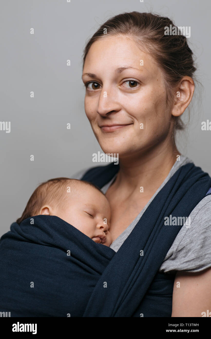 Portrait of smiling mother with baby in baby sling Stock Photo
