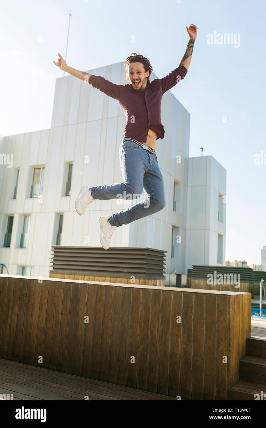 Man on a rooftop terrace, jumping for joy Stock Photo