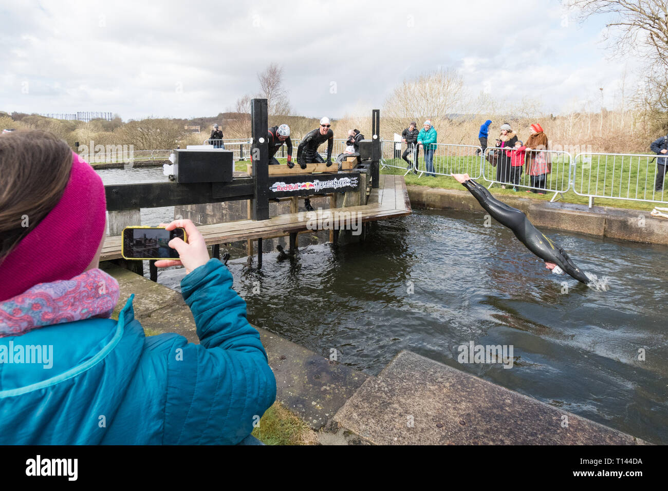 Maryhill, Glasgow, Scotland, UK - 23 March 2019: UK weather - determined competitors braving 8 degree water temperatures at the Red Bull Neptune Steps swim/climb adventure endurance race at Maryhill Locks, Glasgow.  The annual extreme event involves swimming 400m of cold canal water and climbing 18 metres over 7 canal lock gate obstacles Stock Photo