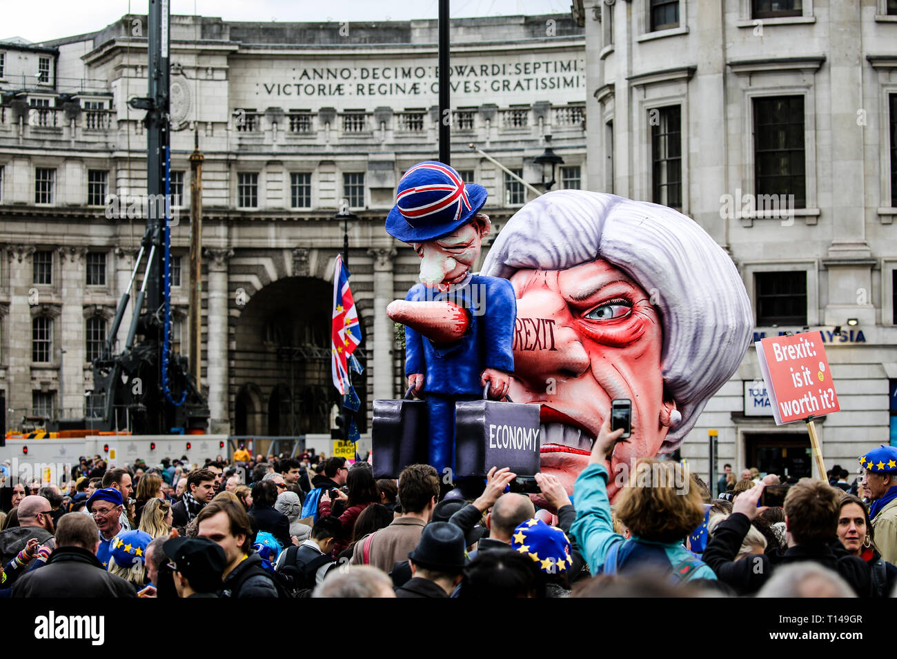 Caricature of Theresa may, Brexit written on her nose, with her nose impaling a figure of a man holding two suitcases labelled 'The economy' The People's Vote March, London, March 2019 Stock Photo