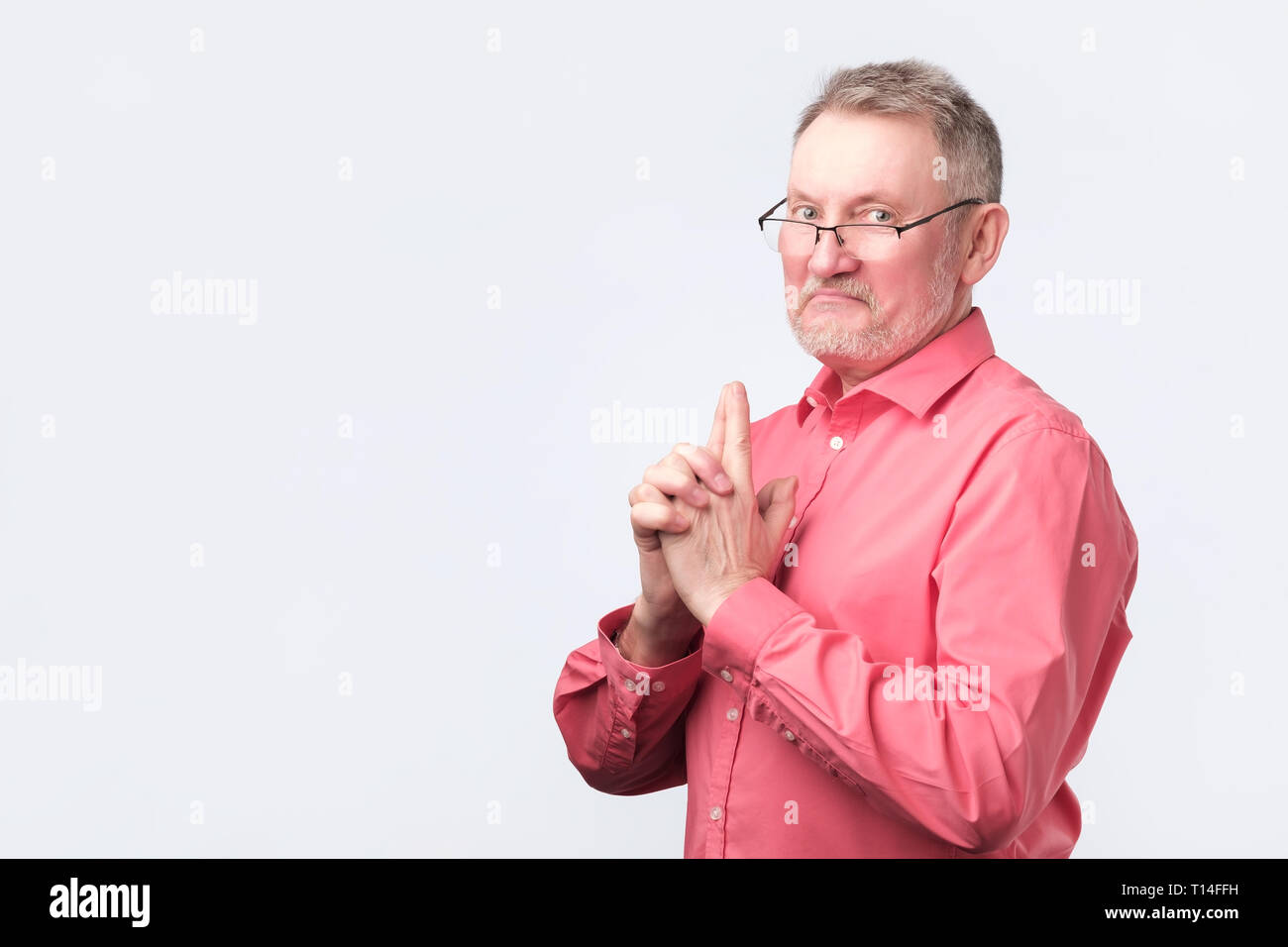 senior man in red shirt showing gun gesture. Stock Photo