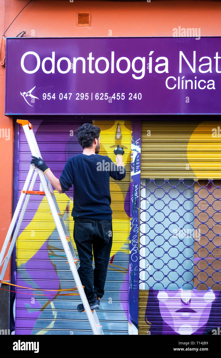 A Street Artist Painting A Picture On The Shutters Of A Dental
