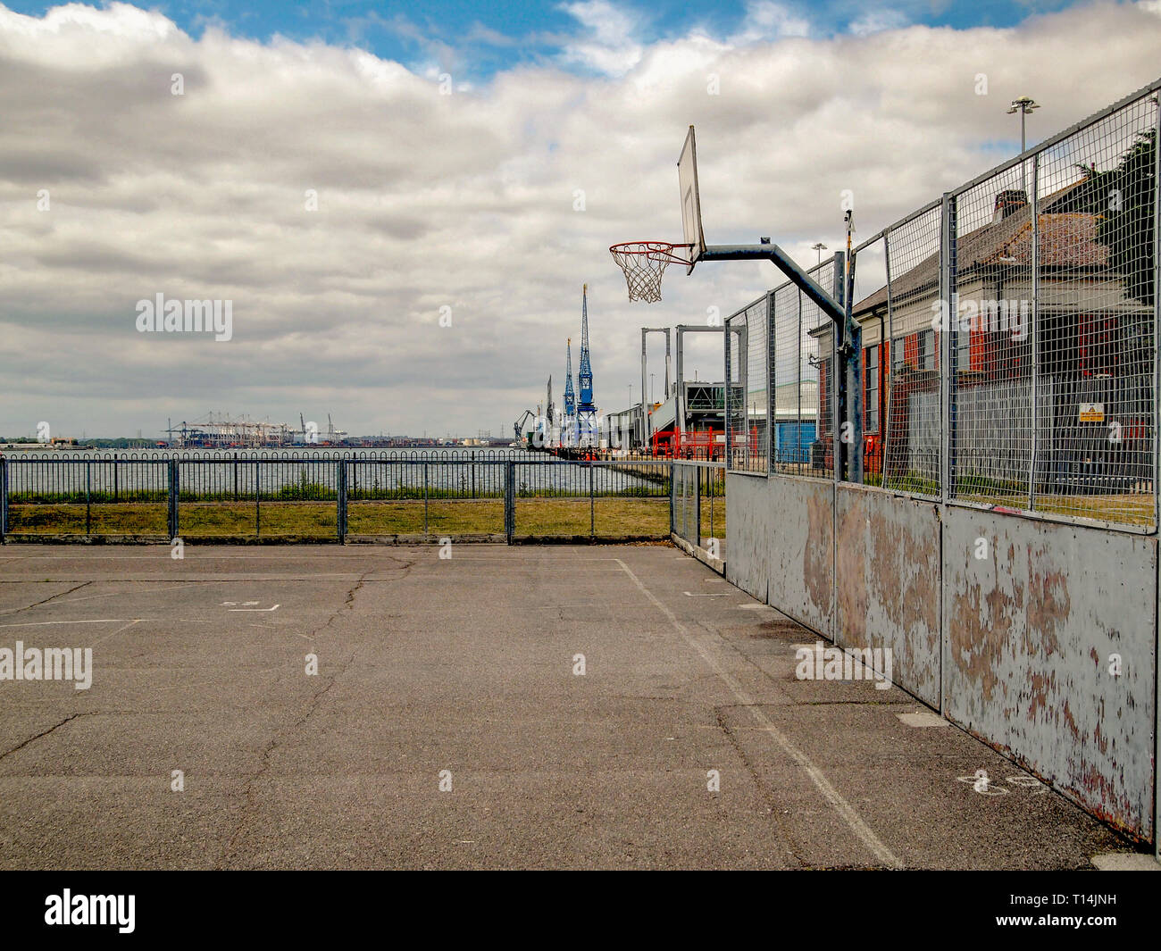 A basketball court in a run down part of a city next to a sea port Stock Photo