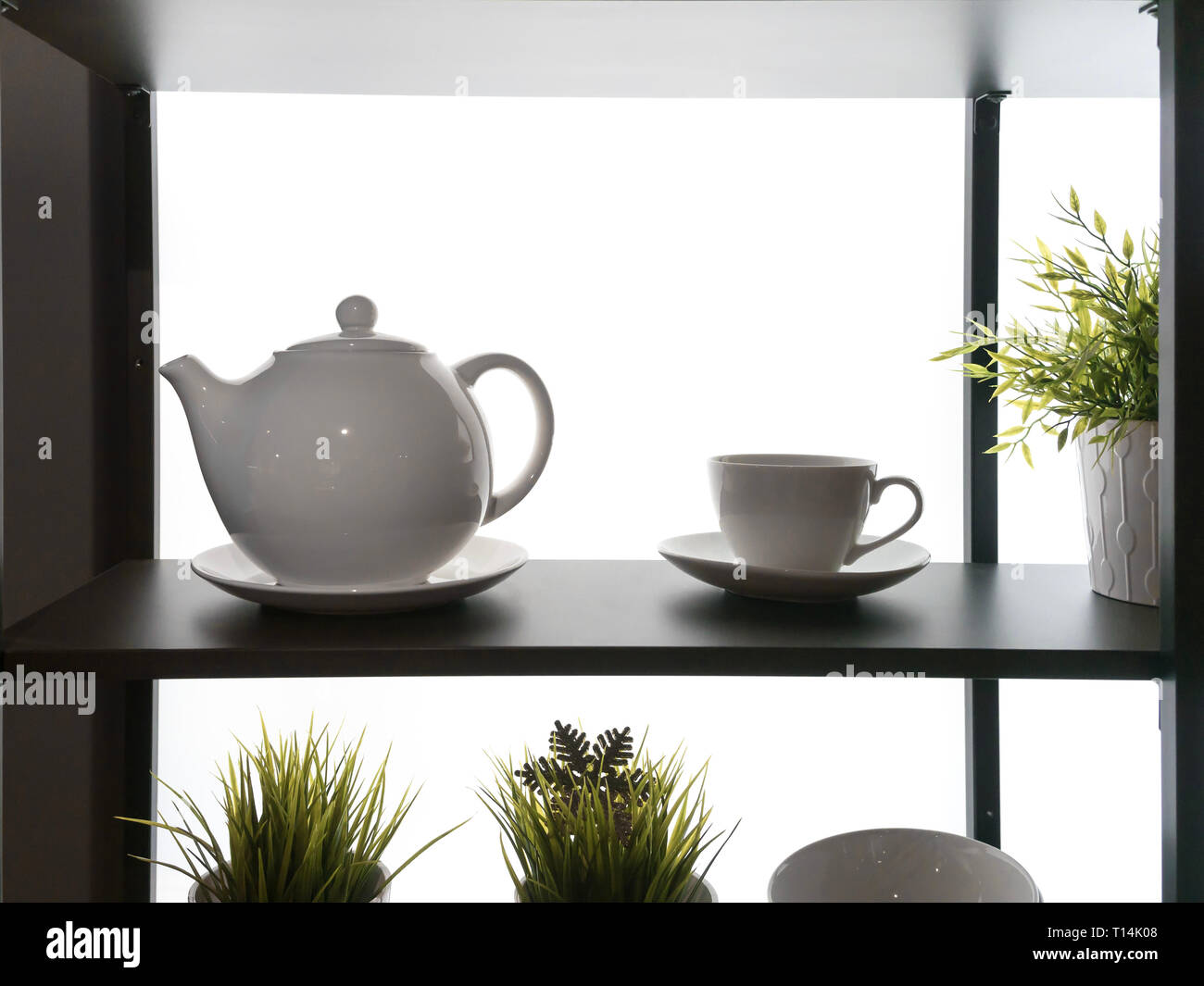 Backlit shelf fragment with kitchenware silhouettes. teapot kettle pot plant on the wooden shelf