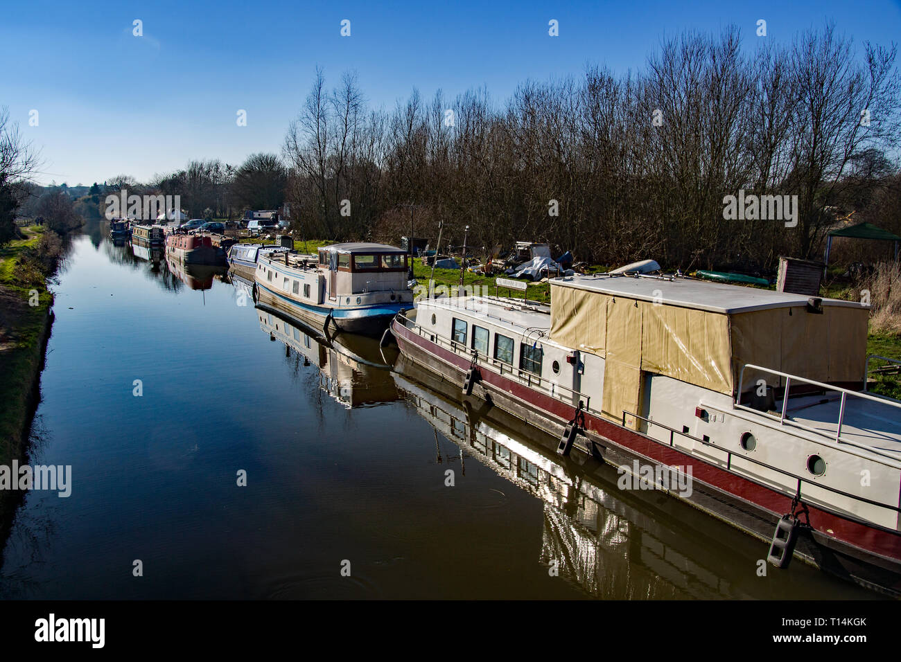 The canal boat and repair yard in Sawbridgeworth with derelict canal boats awaiting repairs on a sunny day in winter. Stock Photo
