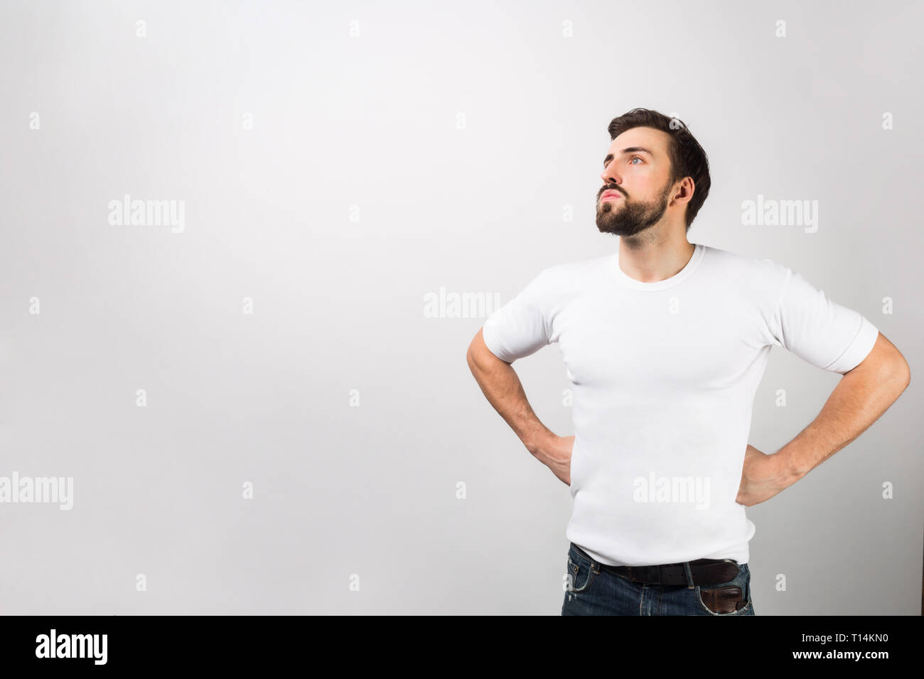 This man is standing in a position of a hero putting his hands on his hips. He is dreaming about better times or the future. That guy looks very serio Stock Photo