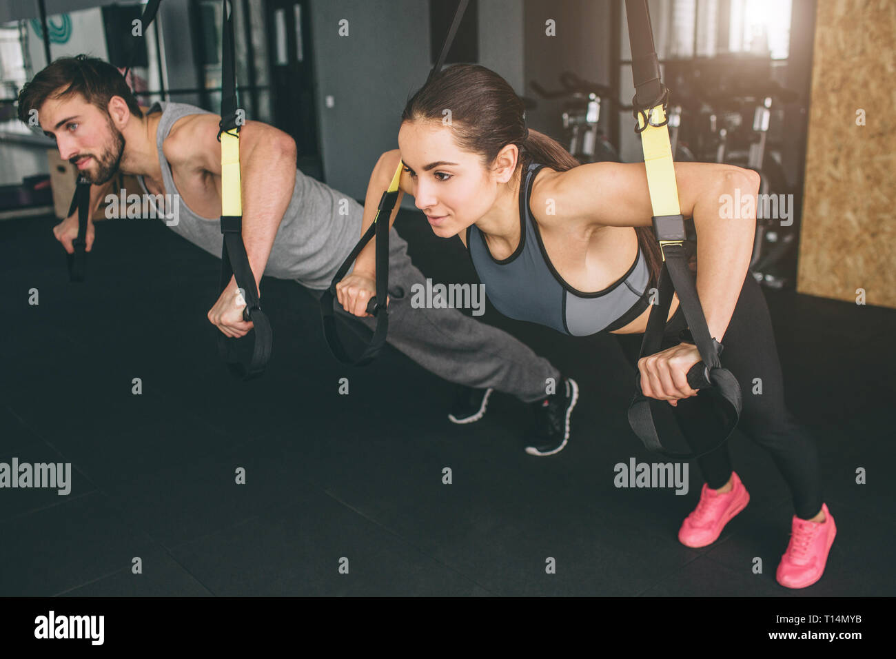Young fitness woman, stands on push up bars stand, doing plunk
