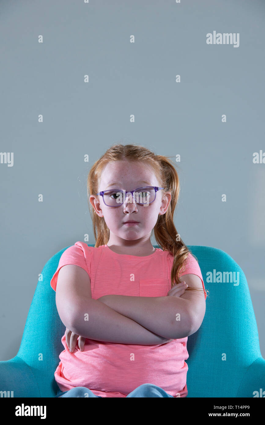 a bored young white girl with glasses and red hair. Stock Photo